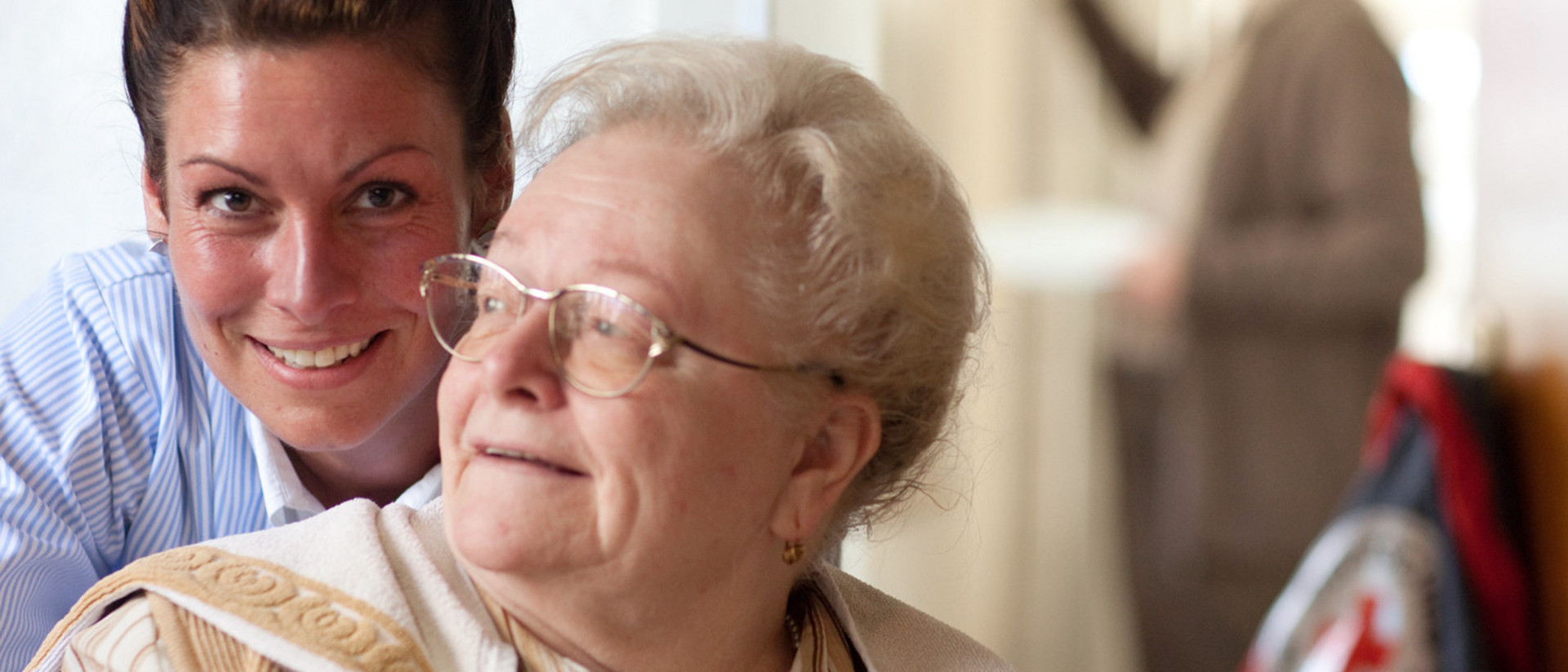 Ältere Dame mit Pflegerin lächeln in die Kamera